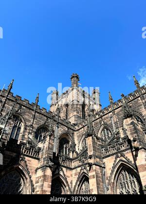 Blick nach oben auf die Kathedrale von Chester mit rotem Sandsteinturm vor klarem blauem Himmel an einem sonnigen Tag, der historische Architektur und Kontrast einfängt Stockfoto