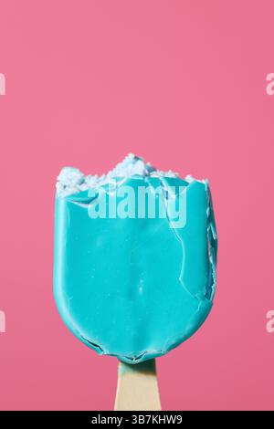 Blau gebissene Eisbar auf Holzstock glasiert auf rosa Hintergrund, bunte Lebensmittelnähe Stockfoto