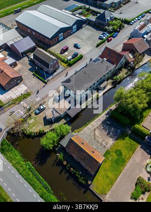 Aus der Vogelperspektive auf ein niederländisches Dorf mit Häusern, Kanälen, Straßen und Industriegebäuden. Die friedliche Szene zeigt eine Mischung aus Wohn- und Geschäftsviertel Stockfoto