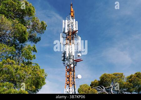 Zellenturm vor dem Hintergrund von grünen Bäumen und blauem Himmel. Nahaufnahme. Stockfoto