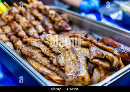 Spieße, Schweinebauch und Würstchen, die über Holzkohle gegrillt werden Stockfoto