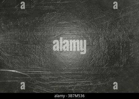 Dunkle grunge metallische Hintergrundstruktur mit markanten Kratzern und einer subtilen Lichtreflexion in der Mitte.Weißrussland Stockfoto
