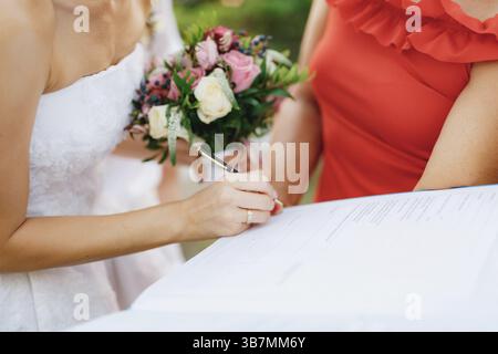 Die Braut unterschreibt die Hochzeitsurkunde während der Hochzeitszeremonie aus nächster Nähe. Stockfoto