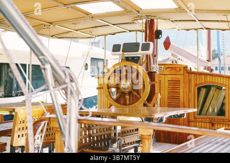 Hölzerne Kapitänsbrücke auf einer weißen Yacht mit einem schönen Lenkrad und Klapptischen. Stockfoto