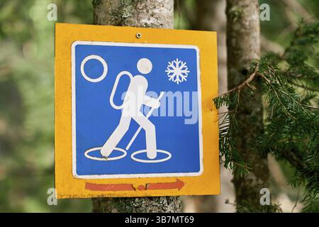 Schild für den Winterwanderweg, das an einem Baum im Wald hängt. Stockfoto