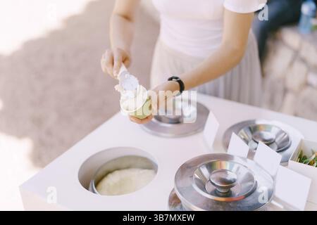 Eisverkäufer legt das Eis in die Tasse. Stockfoto