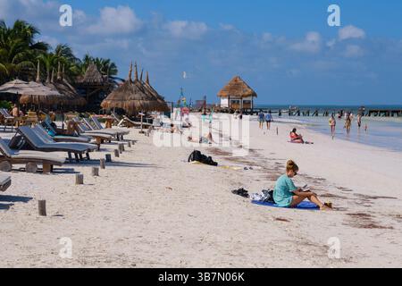 Holbox, Mexiko - 9. Februar 2025: Touristen entspannen sich auf Liegestühlen und Handtüchern am Strand von Holbox. Stockfoto