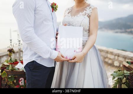 Die Braut und der Bräutigam nehmen eine Heiratsurkunde in den Händen, Nahaufnahme. Stockfoto