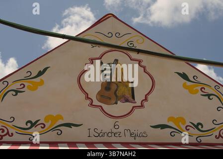 Handgemalte Caseta-Fassade in La Feria de Sevilla 2025 mit spanischer Gitarre und Schal, die Flamenco und andalusische Kultur symbolisieren. Stockfoto