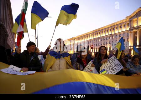 Sofia, Bulgarien - 24. März 2022: Während einer Demonstration zur Unterstützung der Ukraine einen Monat nach Russi reagieren Menschen, die die ukrainische Nationalflagge halten Stockfoto