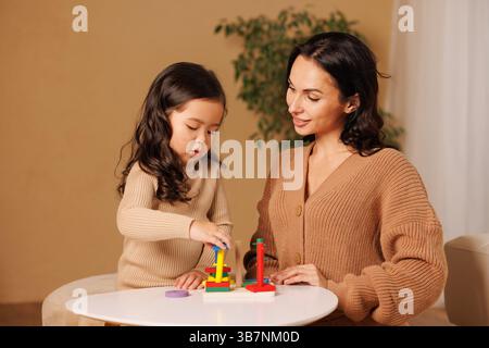 Mutter und Tochter spielen zusammen mit pädagogischem Holzspielzeug und fördern so das Lernen, die Entwicklung und die Bindung. Stockfoto