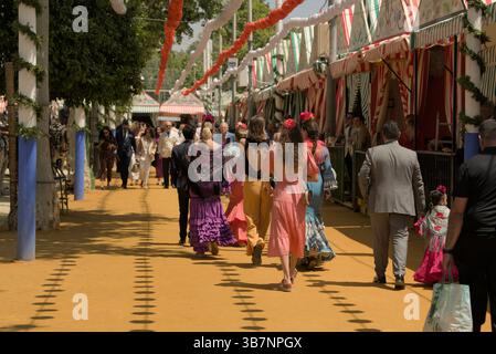 Besucher in farbenfroher Flamenco-Kleidung spazieren entlang der Kasetten in La Feria de Sevilla 2025.Feria de Sevilla, Spanien Stockfoto