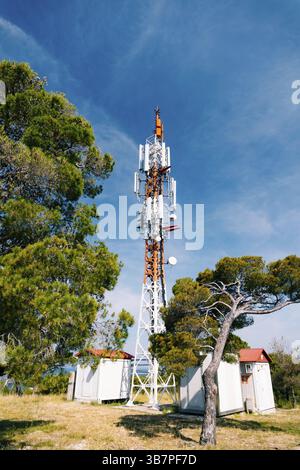Zellenturm vor dem Hintergrund von grünen Bäumen und blauem Himmel. Stockfoto