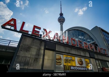 Legendärer Alexanderplatz-Schriftzug am Bahnhofseingang mit dem Berliner Fernsehturm im Hintergrund an einem klaren Frühlingstag in Deutschland. Stockfoto