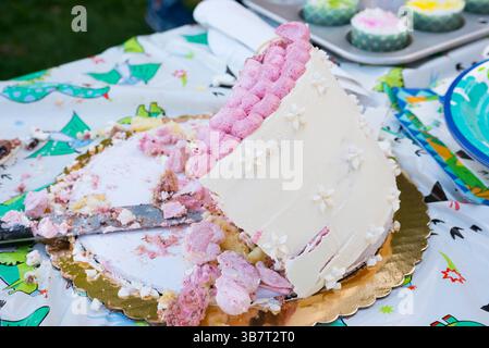 New York City, New York, USA: Teilweise gegessen Vanillegeburtstorte mit Himbeerdekorationen, die auf Goldfolie zusammenfallen, Deckchen mit Cupcakes in Cupcake Dose im rechten Hintergrund (Credit Image: © Novo Images/Glasshouse via ZUMA Press Wire) Stockfoto