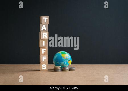 Zölle, Wort auf gestapelten quadratischen Holzblöcken. Neben Miniaturkugel und Münzen. Stockfoto