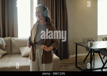 Ältere Frau, die Musik mit Kopfhörern hört Stockfoto
