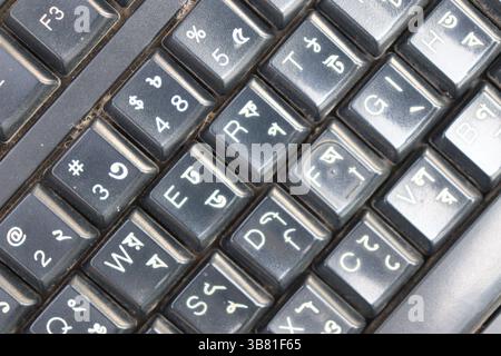 Detaillierte Nahaufnahme der Tasten einer zweisprachigen Tastatur mit englischen und bengalischen Alphabeten, die einen klaren Überblick über das Layout der Tastatur bieten Stockfoto