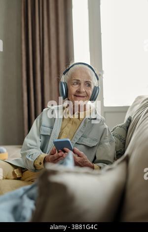 Musik hören mit Kopfhörern im gemütlichen Wohnzimmer Stockfoto