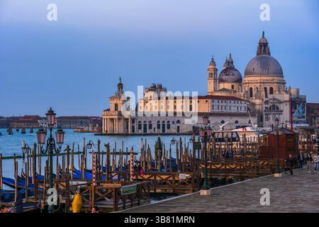 Stadt Venedig bei Sonnenaufgang in Italien. Basilika di Santa Maria della Salute im Viertel Dorsuduro, Blick von der Uferpromenade Riva degli Schiavoni mit Gondel Stockfoto
