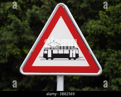 Ein dreieckiges Warnschild, das auf das Vorhandensein von Straßenbahnen hinweist. Das Schild zeigt eine schwarze Silhouette einer Straßenbahn auf weißem Hintergrund, eingerahmt von einem roten Rand Stockfoto