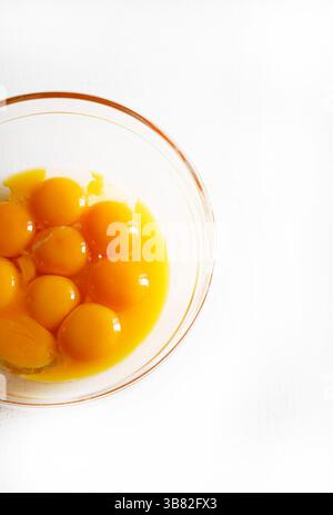Eigelb in einer Glasschale auf einem weißen Tisch. Eigelb für die Teigherstellung. Eigelb zum Kochen. Direkt darüber. Stockfoto