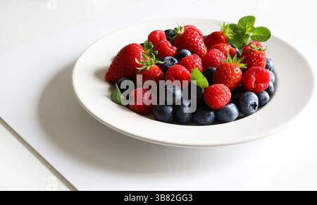 Frische Beeren. Erdbeeren, Heidelbeeren und Himbeeren auf einem Teller isoliert auf weißem Hintergrund. Gesunde Ernährung. Direkt darüber. Stockfoto