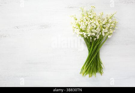 Blumenstrauß von Lilien des Tals auf weißem schäbigen Holztisch. Stockfoto