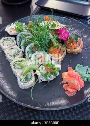 Exquisite Sushi-Platte mit lebhaften Garnituren wie Sternenfrüchten und essbaren Blumen, perfekt für kulinarische Enthusiasten und Liebhaber der japanischen Küche. Stockfoto