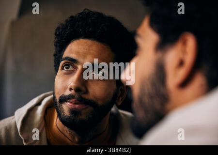 Spiegelreflexion eines Mannes mit lockigem Haar, der wegschaut Stockfoto