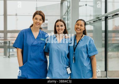 Porträt lächelnder medizinischer Fachkräfte, die im Krankenhauskorridor zusammen stehen Stockfoto