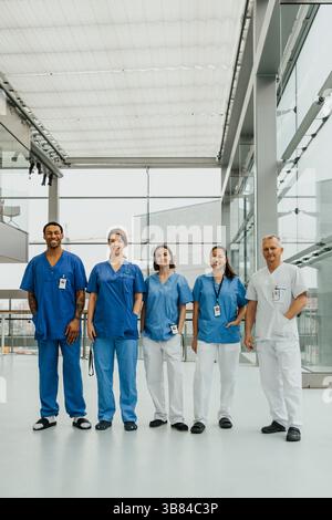 Porträt männlicher und weiblicher Ärzteteams, die nebeneinander im Krankenhauskorridor stehen Stockfoto