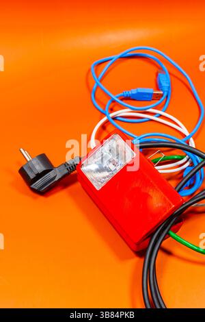 Offene Laterne mit vielen Drähten in verschiedenen Farben auf einer orangefarbenen Oberfläche Stockfoto