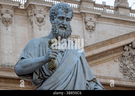 Die monumentale Statue des Heiligen Peter auf dem Petersplatz im Vatikan. Im Hintergrund die Fassade des Petersdoms. Halblange Länge Stockfoto