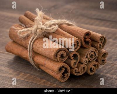Gemahlener Zimt, Zimtstangen, mit Jute Seil auf Holz- Hintergrund gebunden. Nahaufnahme Stockfoto