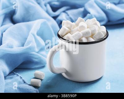 Marshmallows in Tasse auf blauem Hintergrund mit Copyspace. Hintergrundkonzept für Winteressen Stockfoto