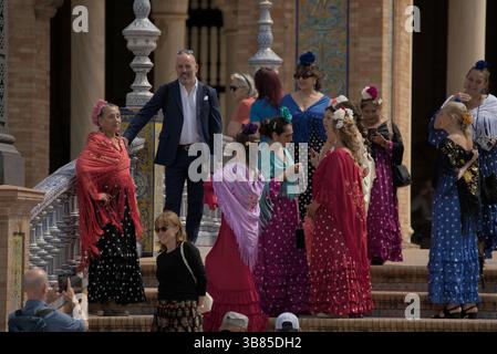 Gruppe von Frauen in bunten Flamenco-Kleidern auf der Plaza de España während der Feria de Sevilla 2025, Sevilla, Andalucía, Spanien. Stockfoto