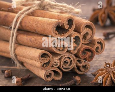 Gemahlener Zimt, Zimtstangen, mit Jute Seil auf Holz- Hintergrund gebunden. Nelke und Sternanis als Hintergrund Stockfoto