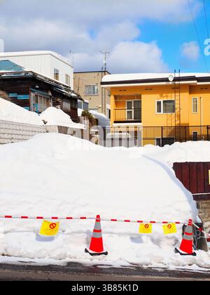 Farbenfrohes gelbes Haus an einem schneebedeckten Hang in Otaru, Hokkaido, Japan Stockfoto