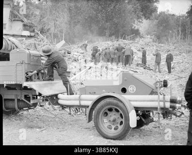 Arbeiter des Zivilschutzes suchen in einem riesigen Schutt- und Holzhaufen nach Überlebenden nach einem verheerenden V1-Angriff in der Highland Road und Lunham Road in Upper Norwood. Ein Feuerwehrmann der Nationalen Feuerwehr bereitet sich darauf vor, Ausrüstung von einem LKW zu heben. Die V-1 und V-2 waren furchterregende Waffen, hatten aber keinen Einfluss auf den Ausgang des Krieges. Die V-1 war eine fliegende Bombe, die fiel, als ihr Treibstoff ausging. Die V2 war eine ballistische Rakete. Beide wurden häufig in westeuropäischen Städten eingesetzt. Stockfoto