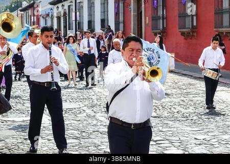 20. März 2024, Antigua, Guatemala: Eine Marschkapelle führt die Semana Santa Festival Queen, umgeben von Schulkindern, während sie in Vorbereitung auf die Holly Week am 20. März 2024 in Antigua, Guatemala durch das historische Zentrum zieht. Die opulenten Prozessionen, detailgetreuen Alfombras und jahrhundertealten Traditionen ziehen mehr als 1 Million Menschen in die alte Hauptstadt. (Bild: © Richard Ellis/ZUMA Press Wire) Stockfoto