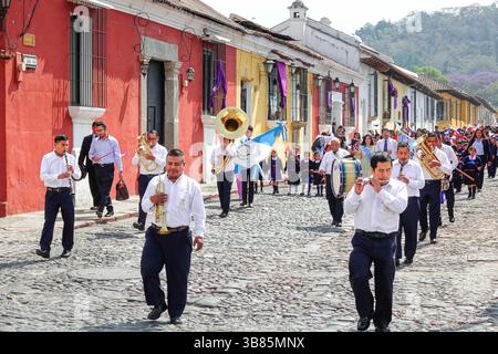 20. März 2024, Antigua, Guatemala: Eine Marschkapelle führt die Semana Santa Festival Queen, umgeben von Schulkindern, während sie in Vorbereitung auf die Holly Week am 20. März 2024 in Antigua, Guatemala durch das historische Zentrum zieht. Die opulenten Prozessionen, detailgetreuen Alfombras und jahrhundertealten Traditionen ziehen mehr als 1 Million Menschen in die alte Hauptstadt. (Bild: © Richard Ellis/ZUMA Press Wire) Stockfoto