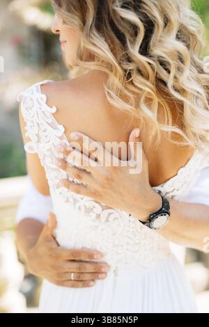 Der Bräutigam umarmt die Braut fest, die Hände des Bräutigams auf dem Rücken der Braut. Stockfoto