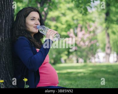 Schwangere Frau trinkt Wasser aus der Flasche Stockfoto