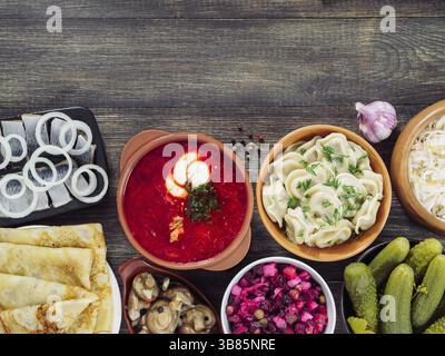 Russische Küche auf hölzernen Hintergrund. Sortiment-Gerichte der russischen Küche - Borschtsch, Pelmeni, Hering, marinierte Pilze, Gurken, Vinaigrett gesalzen Stockfoto