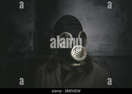 Ein Mann mit einer Gasmaske, der im Dunkeln in einem heruntergekommenen Gebäude bleibt, Bucheinband Stockfoto