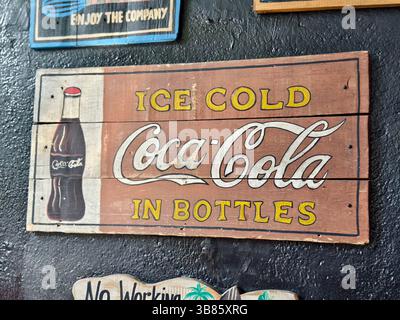 Kuta, Bali, Indonesien – 30. April 2025: Ein rustikales, handgemaltes Holzschild, das Ice Cold Coca-Cola in Flaschen fördert Stockfoto