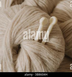 Ästhetisches Bild eines hellen, luftigen, beigen Pastellgarns.Nahaufnahme eines mitteldicken Blasgarns aus Baby-Alpaka und Merinowolle. Stricknadeln n Stockfoto