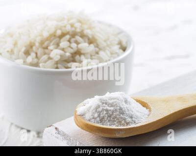 Reismehl im Holzlöffel und Reiskörner auf weißem Hintergrund Stockfoto