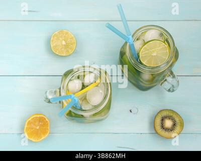 Kalte hausgemachte Limonade mit frischer Zitrone, Limone, Kiwi und Minze in Mason jar. Sommer Drink auf weichem blauem Holz- Hintergrund. Flach oder der Ansicht von oben Stockfoto
